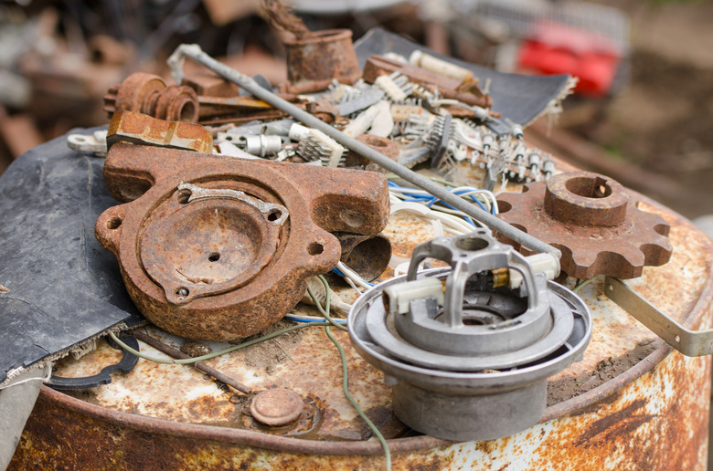 pile of old broken pieces iron lying on rusty barrel