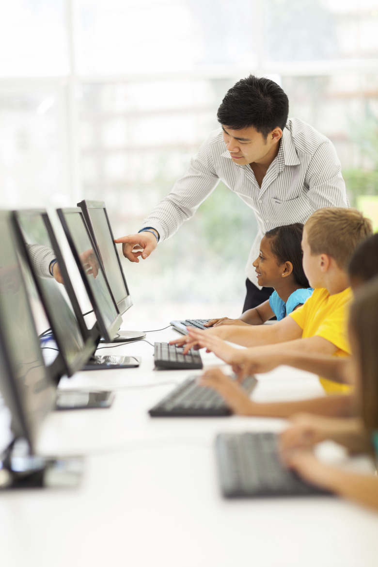 primary school teacher helping student in computer room