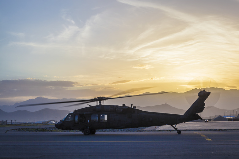 Military utility helicopter on taxiway at sunset