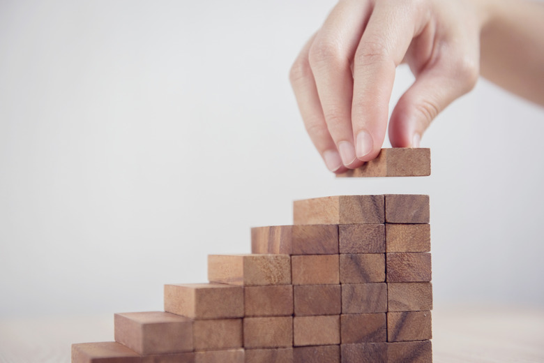 Woman hand arranging wood block stacking as step stair. Business concept growth success process.