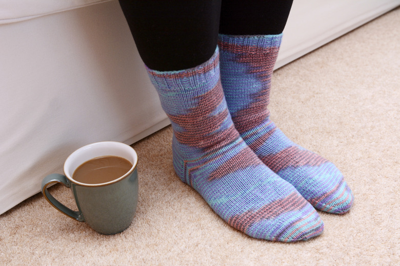 Hot drink on the floor by feet in socks