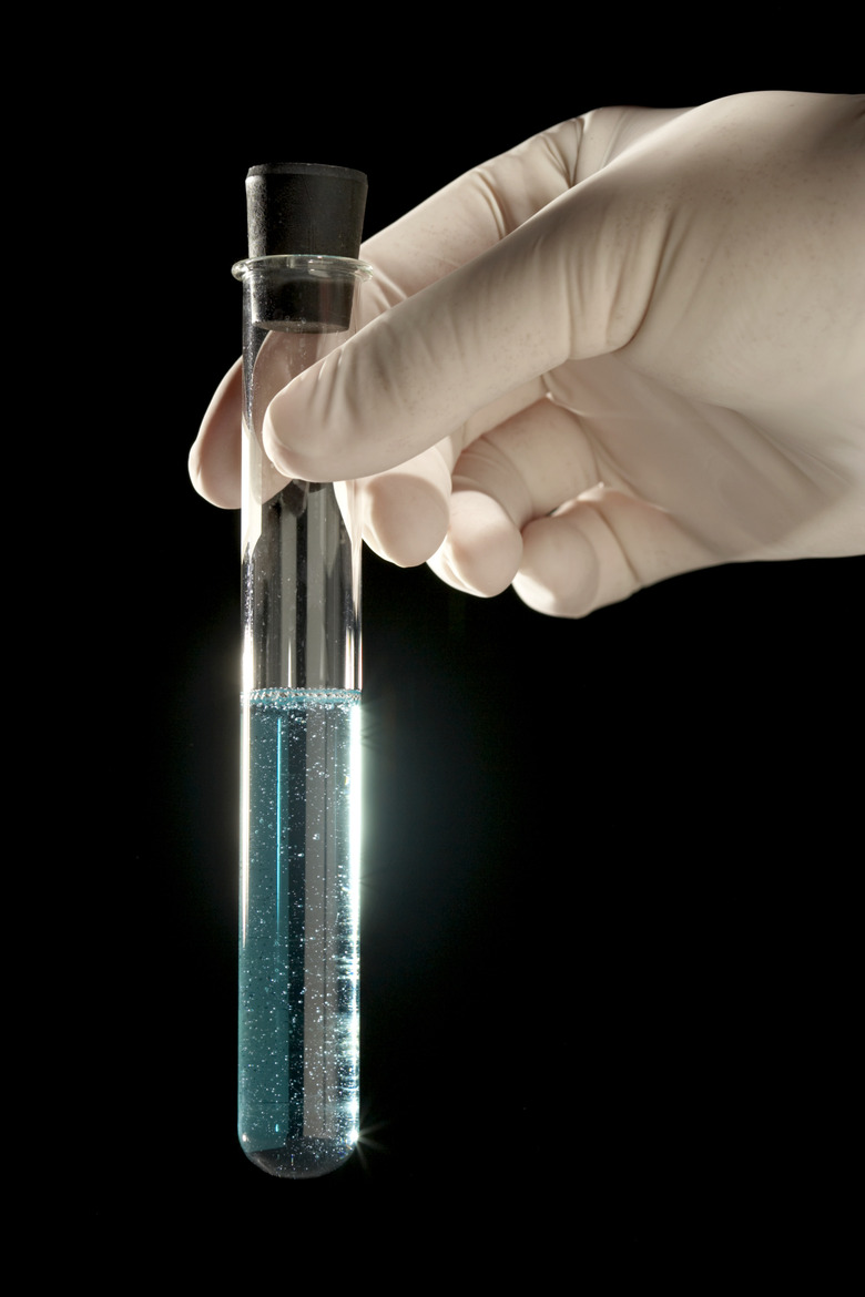 Lab tech holding test tube with blue liquid