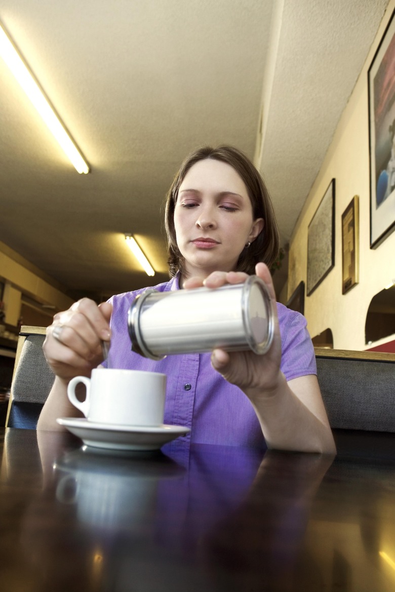 Woman pouring sugar in coffee