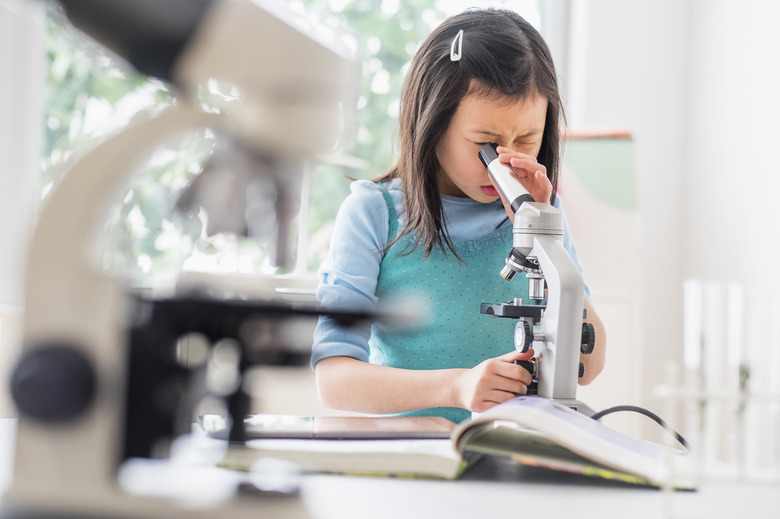 Chinese student using microscope in science lab