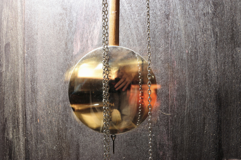 metal pendulum clock swinging in wood background