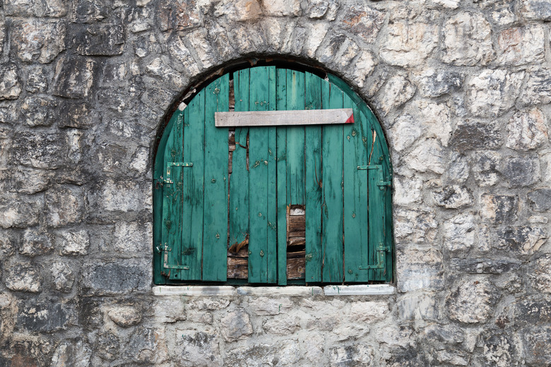 Ancient semicircular window with nailed green wooden shutters.