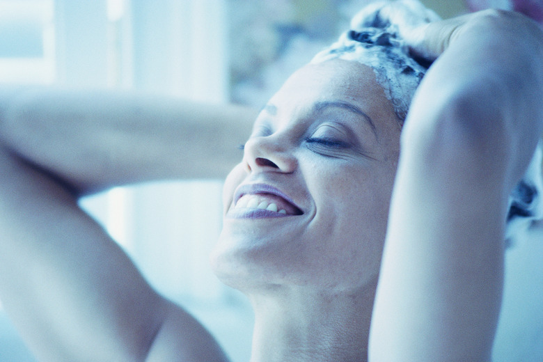 Woman shampooing hair and smiling