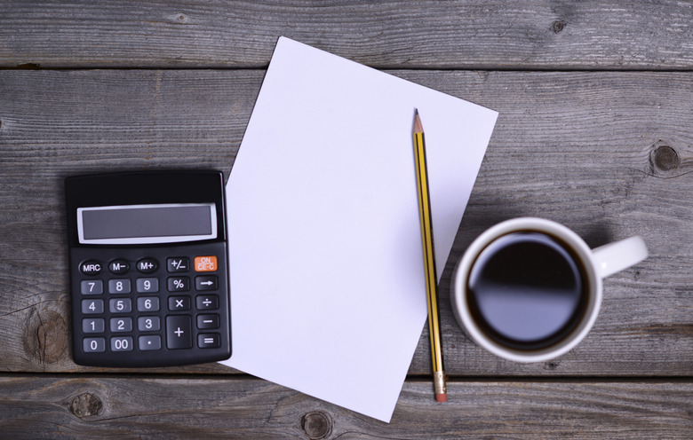 empty paper, pen, calculator and coffee on table