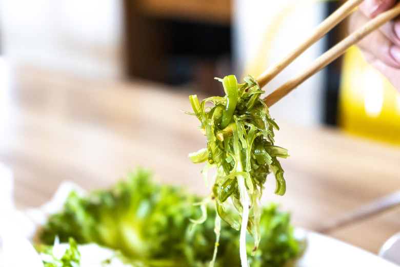 Japanese seaweed salad in chopsticks ready to eat.