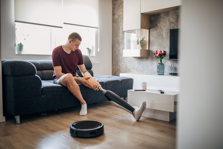 Man with one leg putting on prosthetic leg on sofa