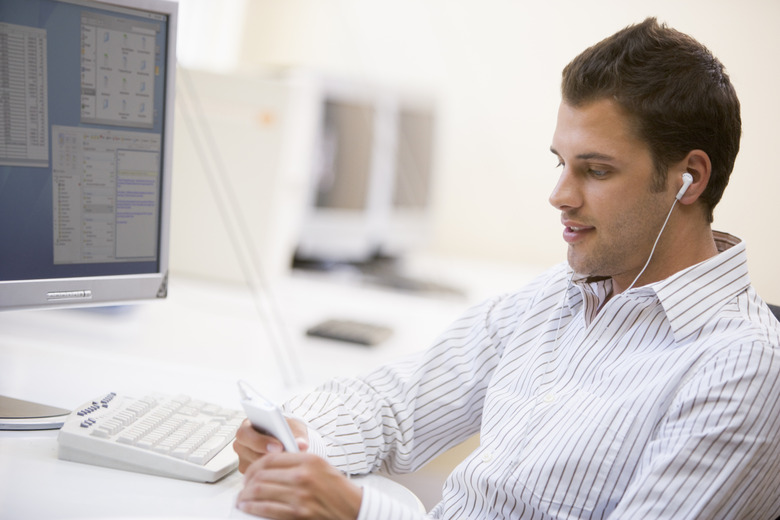 Man in computer room listening to MP3 player