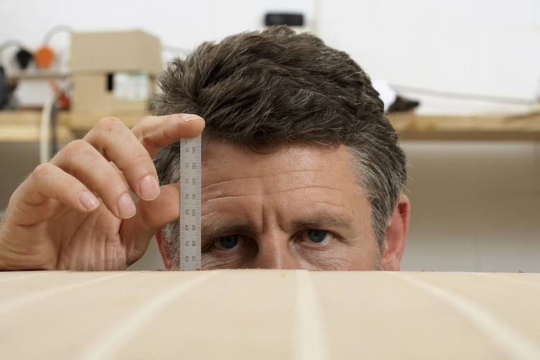 Mature man measuring boat with ruler