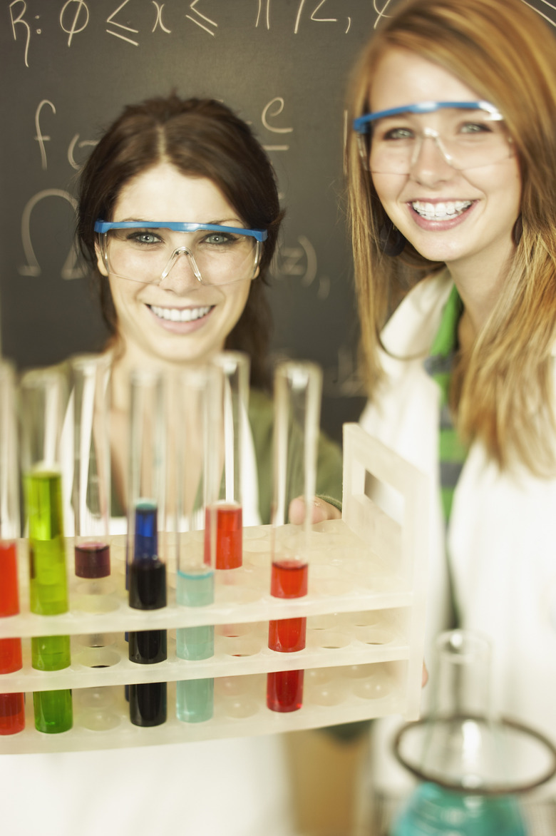 Smiling teenagers performing experiment in science lab