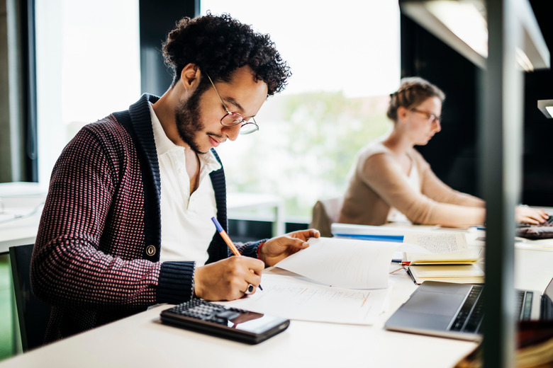 Young Student Concentrating While Studying In Public Library