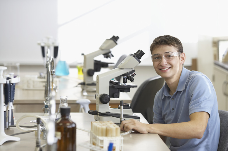 Portrait of a teenage boy in front of a microscope