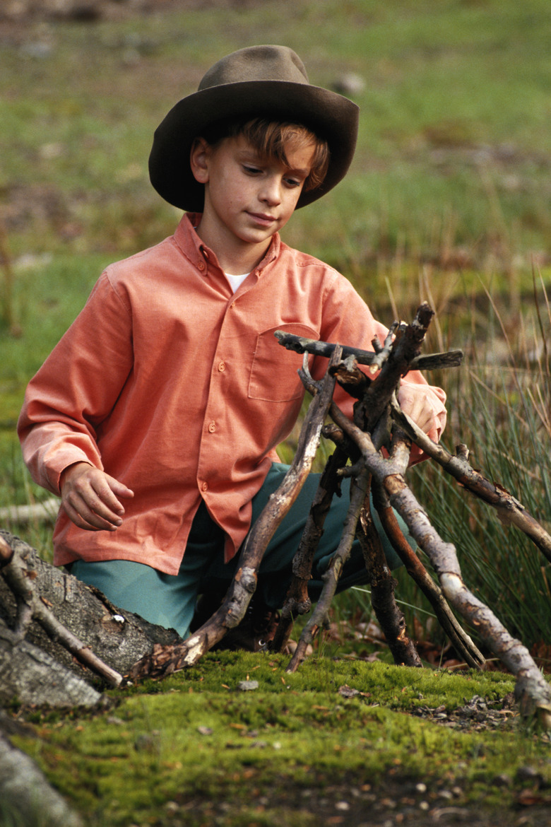 Boy (8-9) preparing campfire