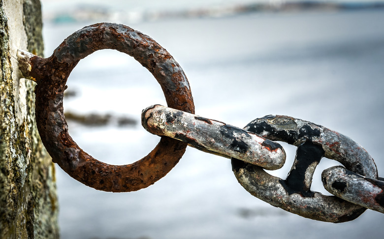 Old rusty anchor iron ship chain in sea port.