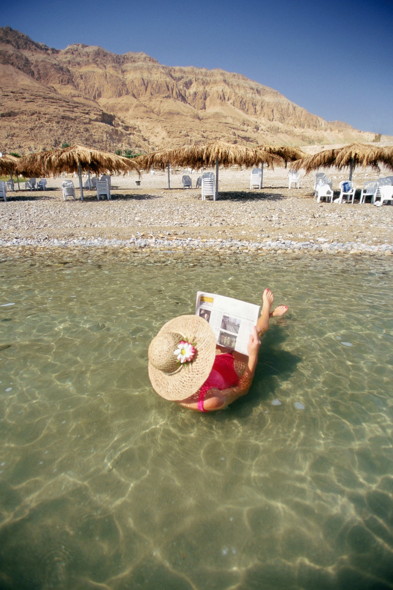 Israel, Dead Sea, Rear view of a woman floating on water and reading a newspaper