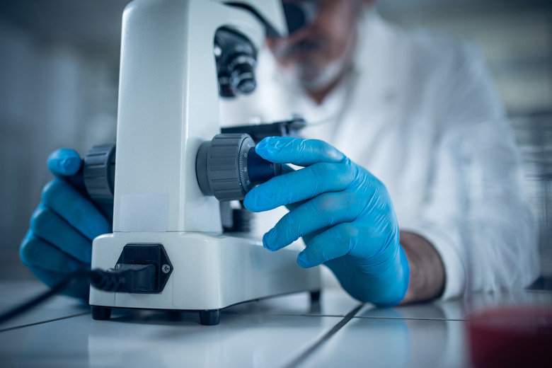 Close up of unrecognizable doctor using a microscope.