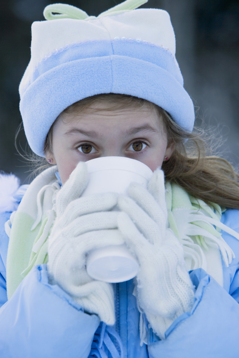 Young girl (6-7) drinking from styrofoam cup in snow, portrait