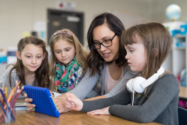 Teacher showing first graders basic programming on a digital tablet