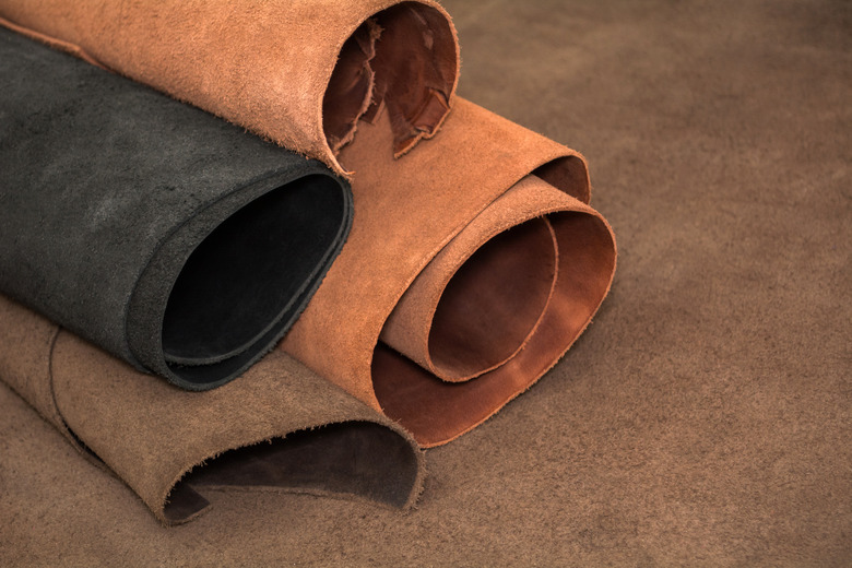 Rolls of natural brown and black leather. Materials for leather craft