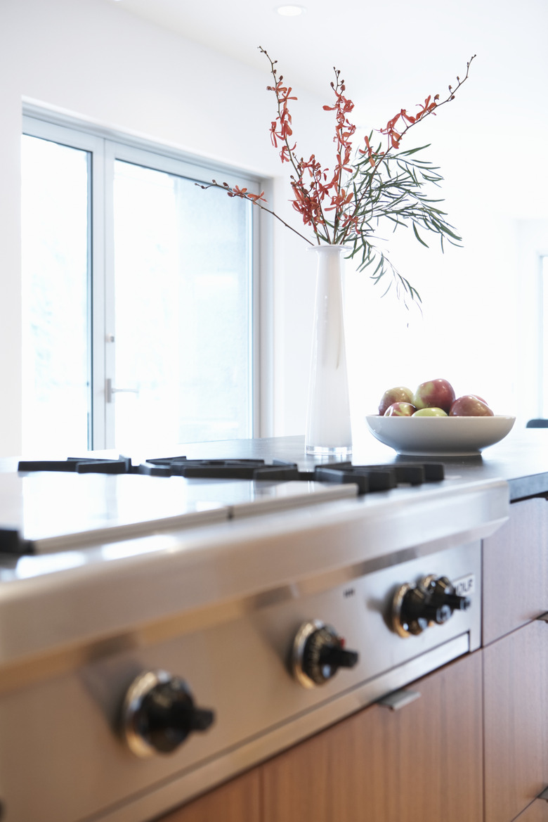 Flowers and bowl of fruit beside stove in domestic kitchen