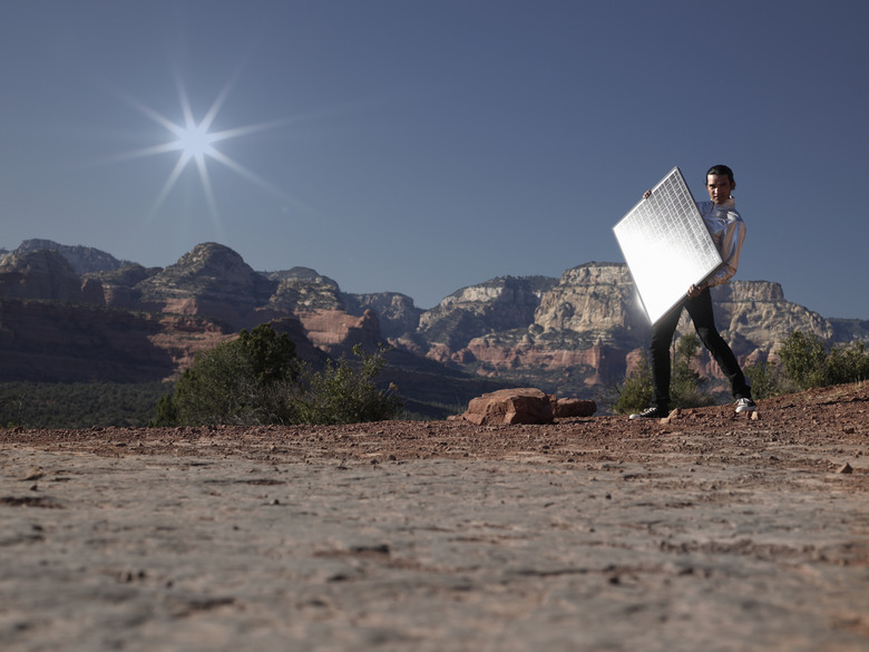 Young man with solar panel, side view