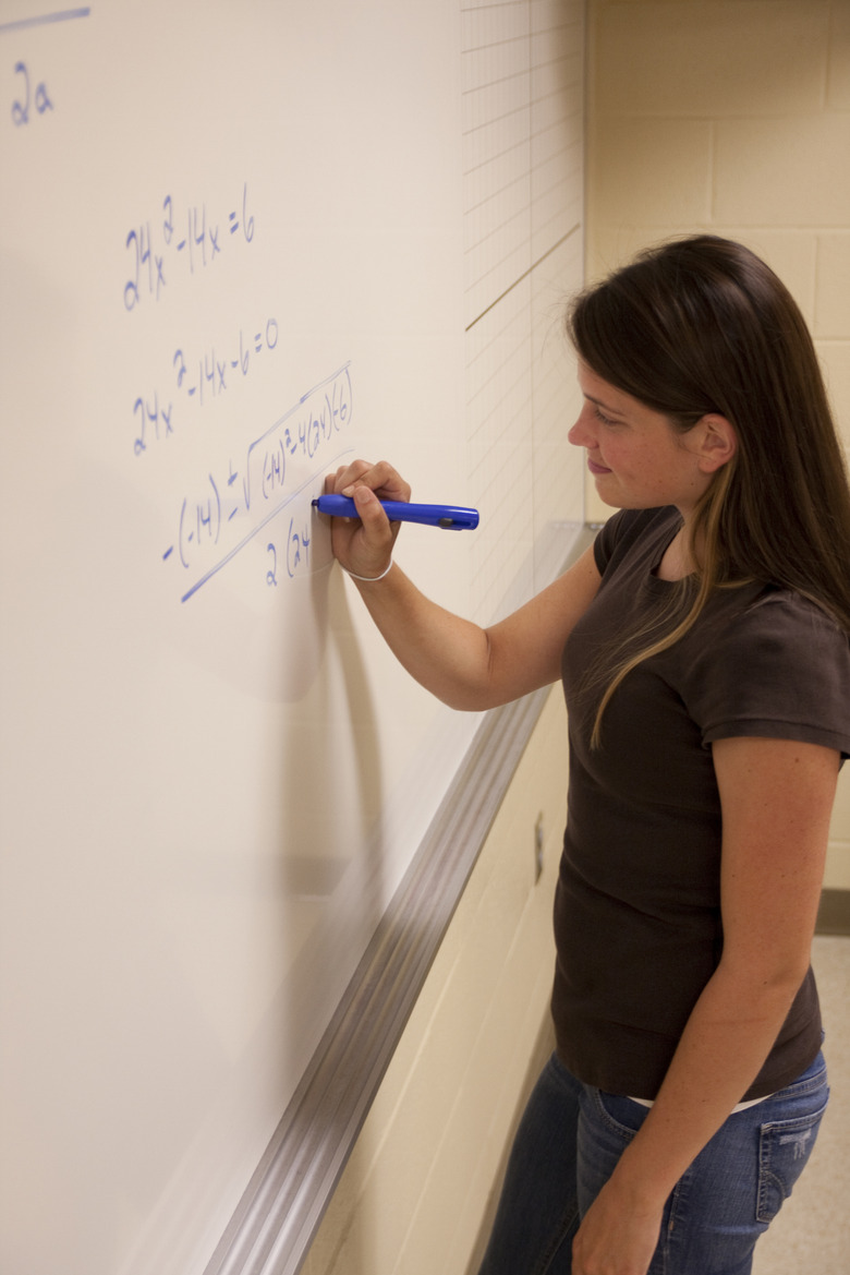 Female student solving an Algebra equation on a whiteboard.