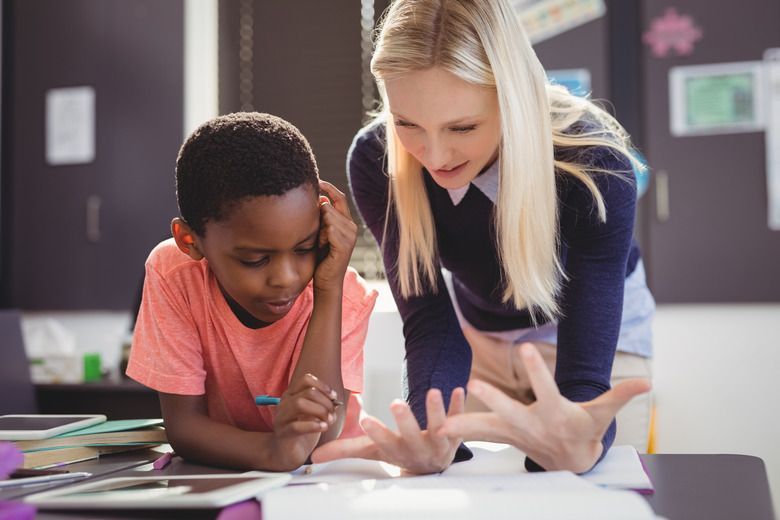 Teacher helping schoolgirl with her homework in classroom