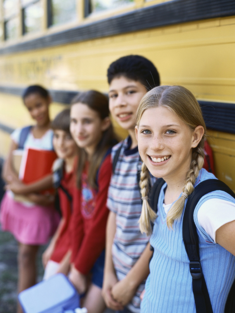 Side profile of five children waiting outSide the school bus