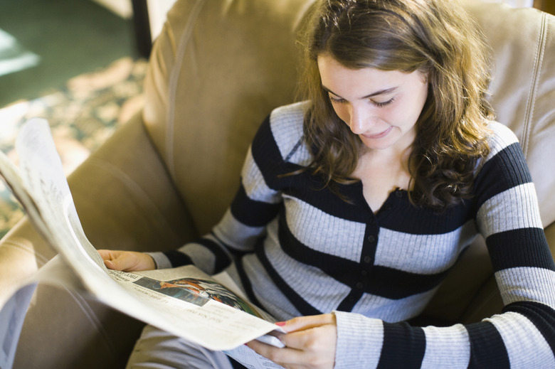 Teenage girl reading a newspaper