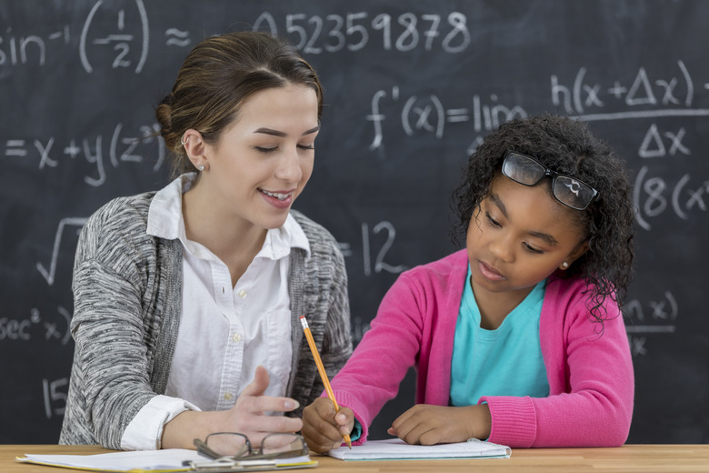 Math teacher helps elementary schoolgirl with math assignment