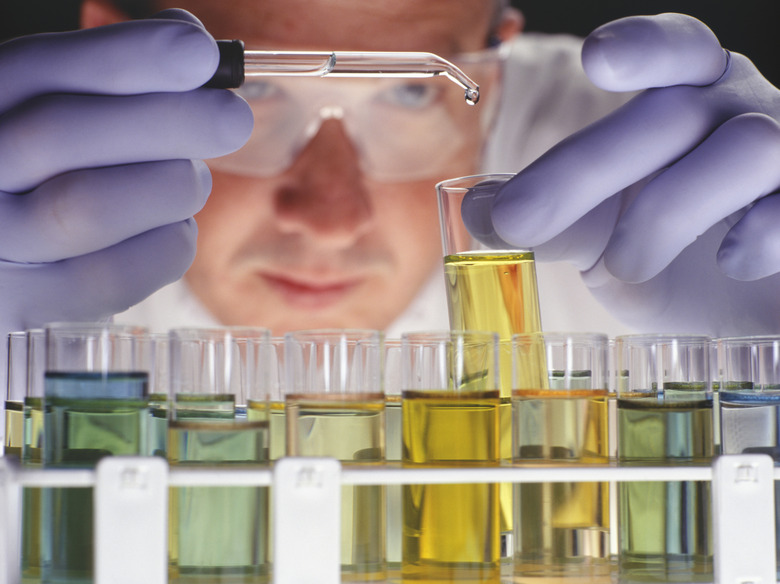 Chemist dropping liquid into test tubes, close-up