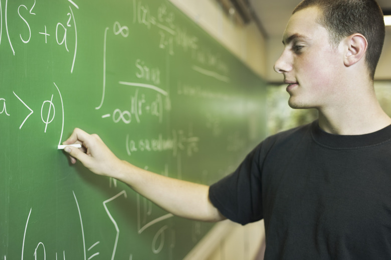 Teenage boy writing on chalkboard