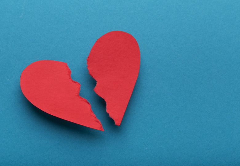 Broken paper heart on blue background, top view