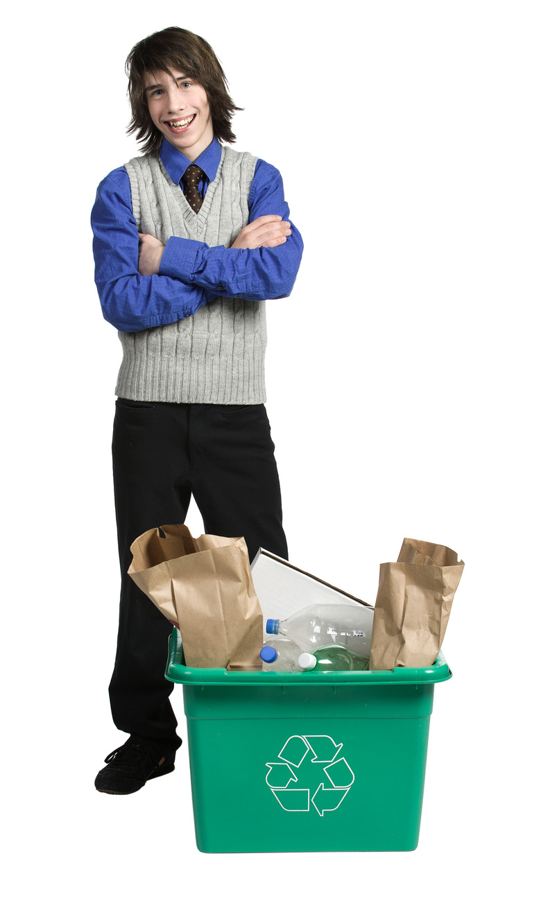 Teenage boy posing next to full recycling bin