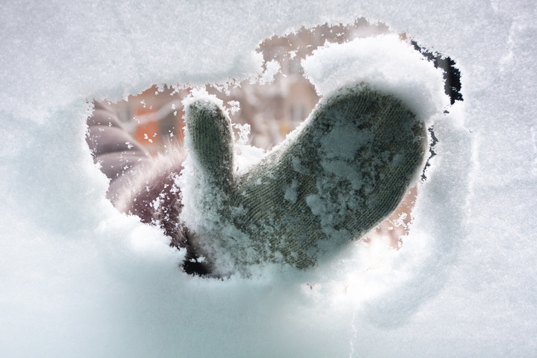 hand in mitten cleaning window of car