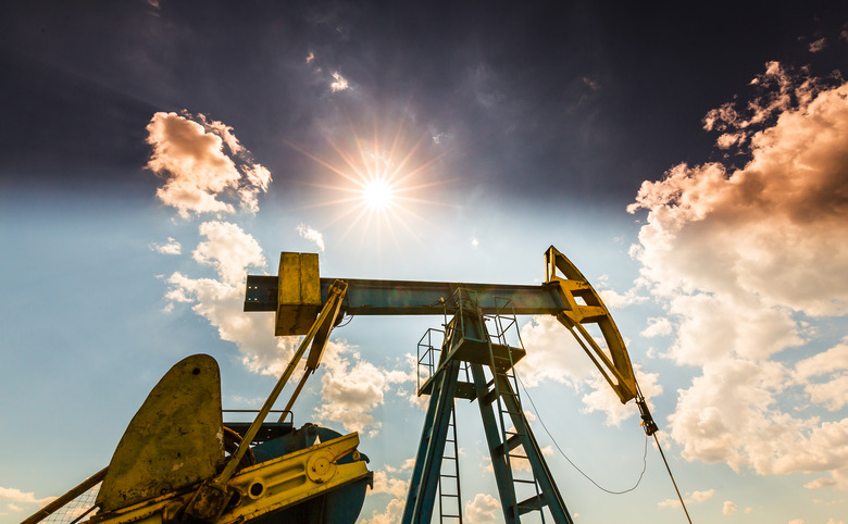 Oil field with pump jack, profiled on blue sky with white clouds, on a sunny day