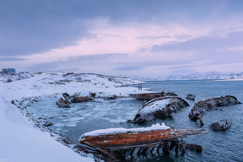 Wooden parts of old ships on the Barents Sea coast at sunrise. Ship cemetery, Teriberka, Murmansk Region, Kola Peninsula. Russia.