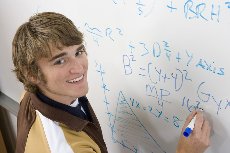 Male student writing maths equations on whiteboard