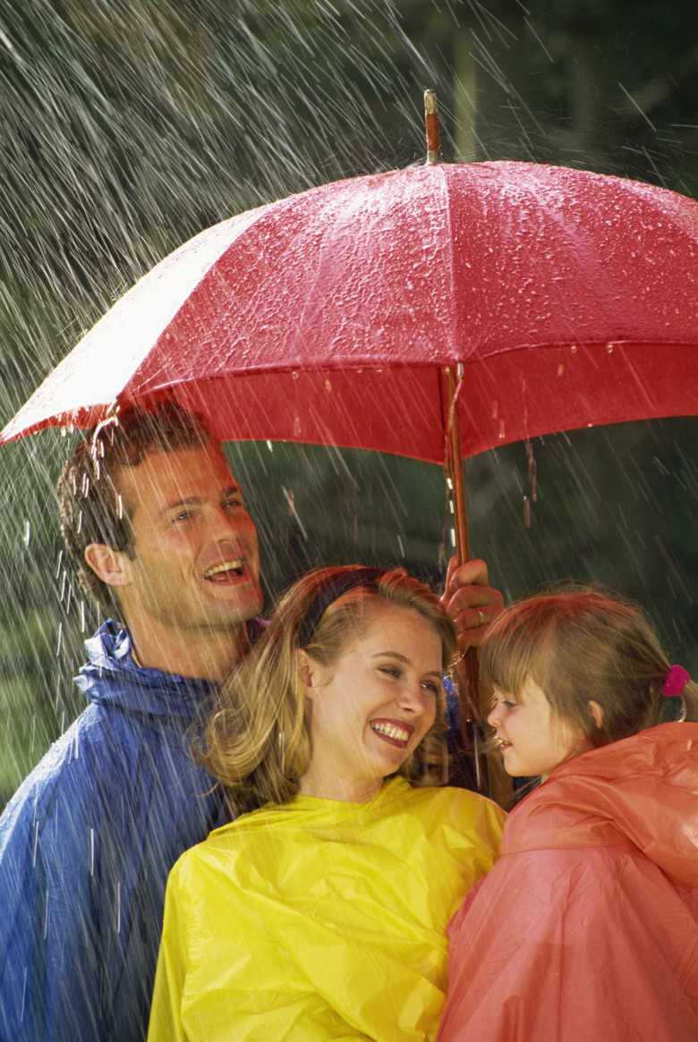 Family standing under umbrella in the rain