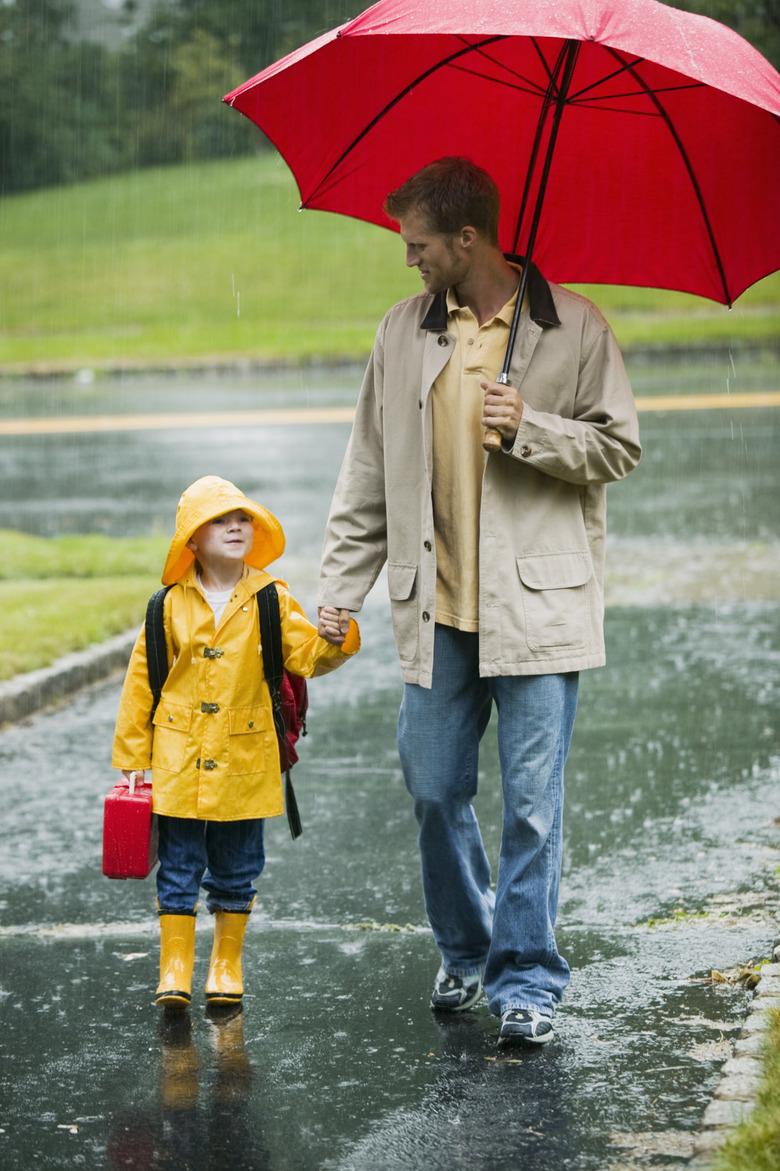 Father and child walking in rain