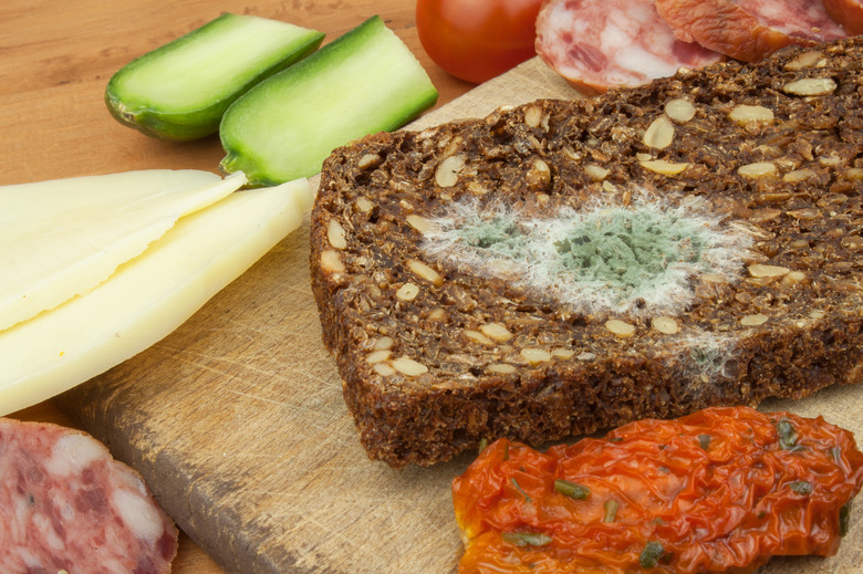 Moldy bread in wooden table. Unhealthy food. Spoiled food.