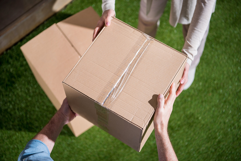 Cropped shot of couple holding cardboard box, relocation concept